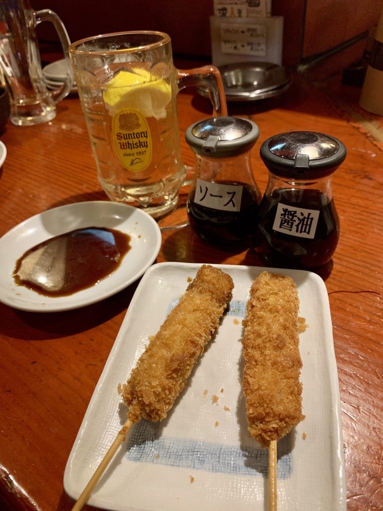 yakitori on a plate with a suntory whiskey inside an izakaya